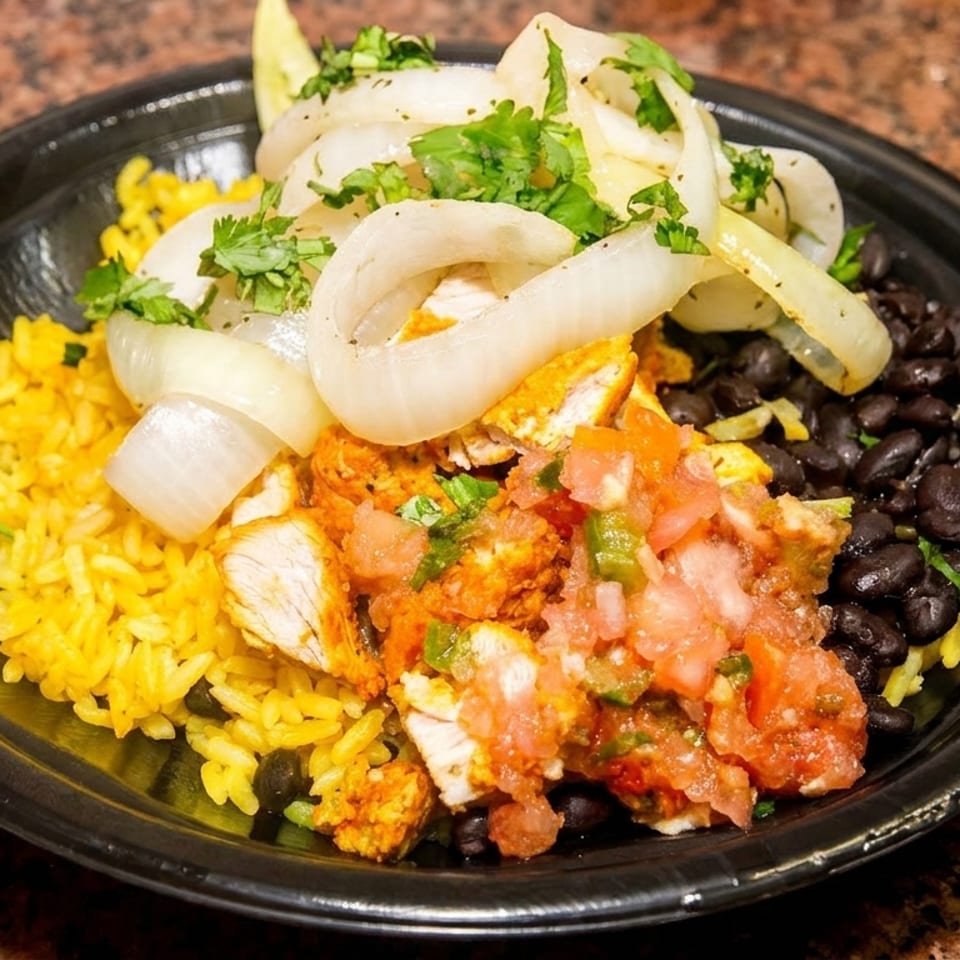 A black bowl filled with yellow rice, black beans, chicken, pico de gallo, and onions.