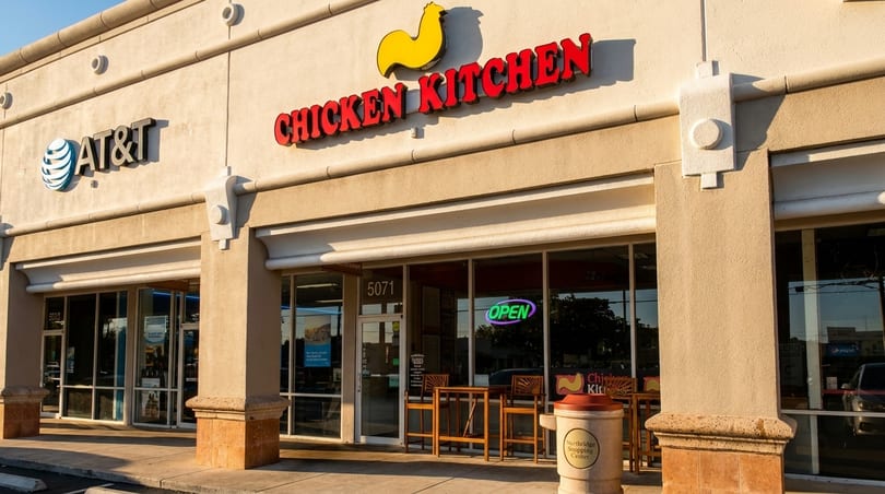 Exterior of Chicken Kitchen restaurant with a yellow chicken logo and red lettering, next to an AT&T store.