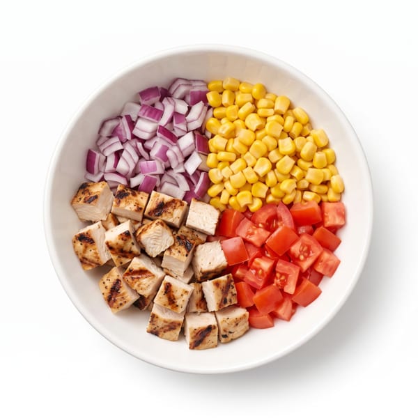 A white bowl containing diced grilled chicken, red onion, corn, and tomatoes.